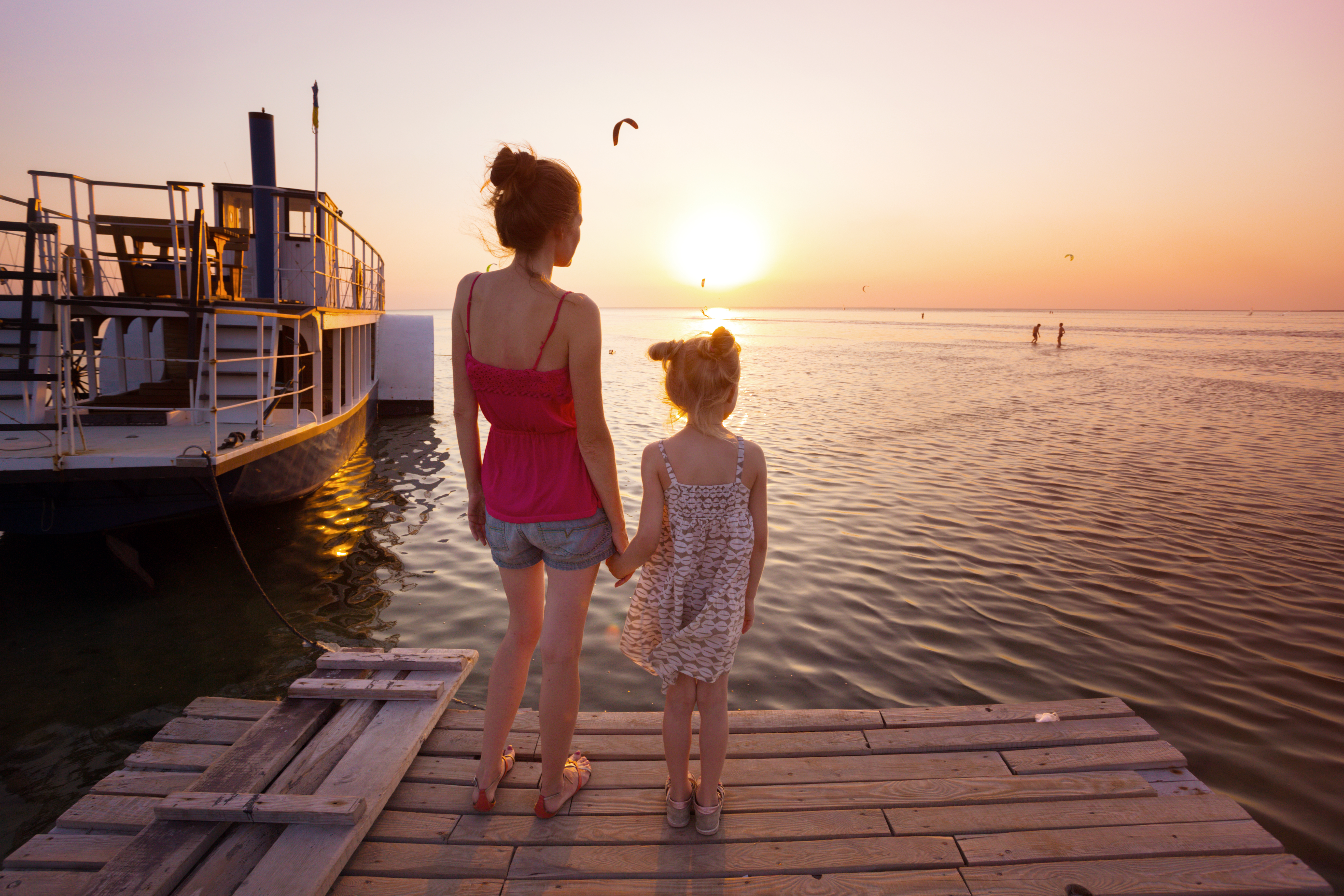 Mother and daughter standing on the pier famille profitant d'une croisière au coucher du soleil en Guadeloupe sur un bateau