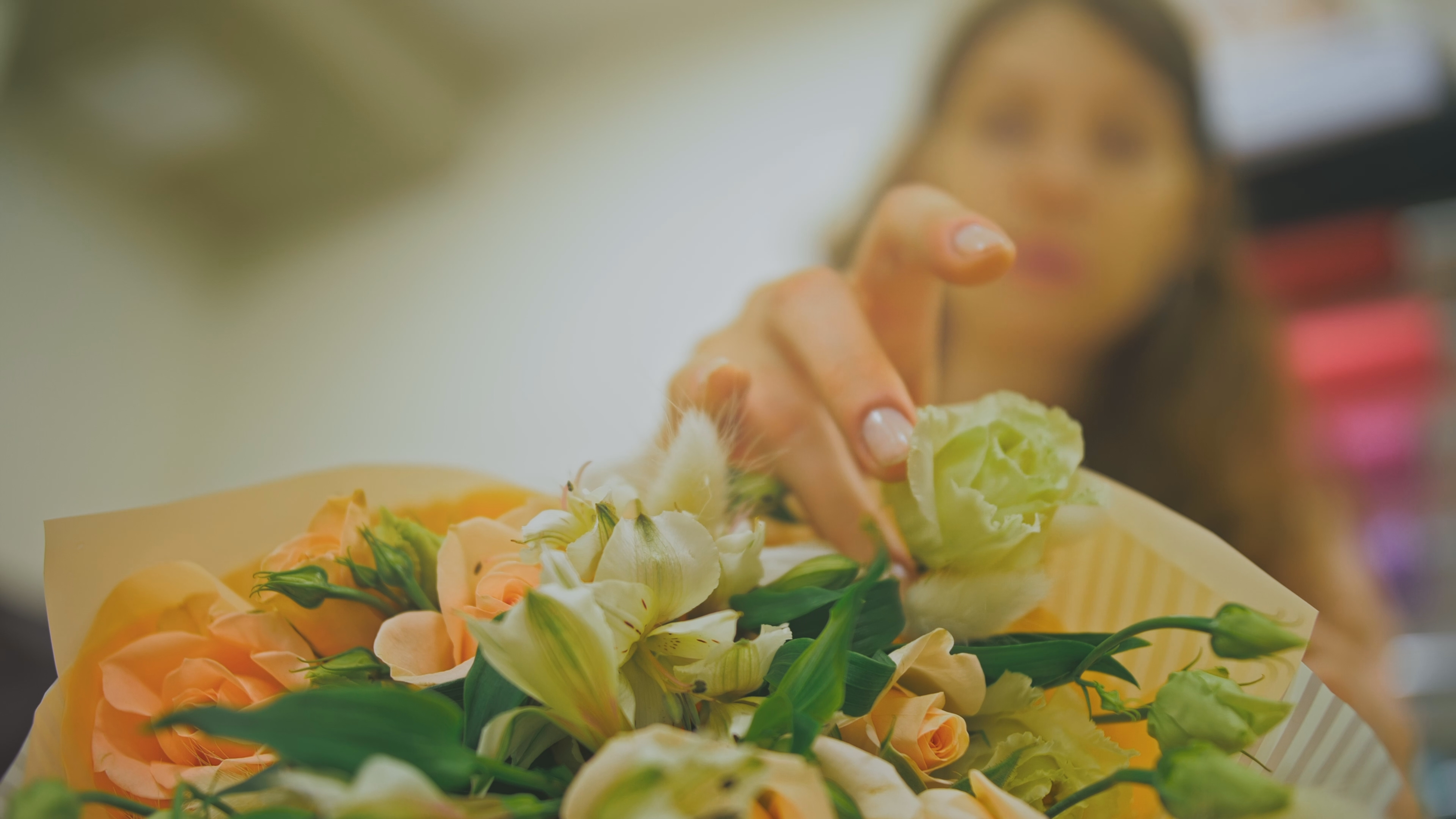 Female florist makes flower bunch, she cuts off wrapping paper working in flower shop. Cute young professional makes bouquet in floral store. Fleuriste préparant un bouquet exotique pour livraison en Guadeloupe