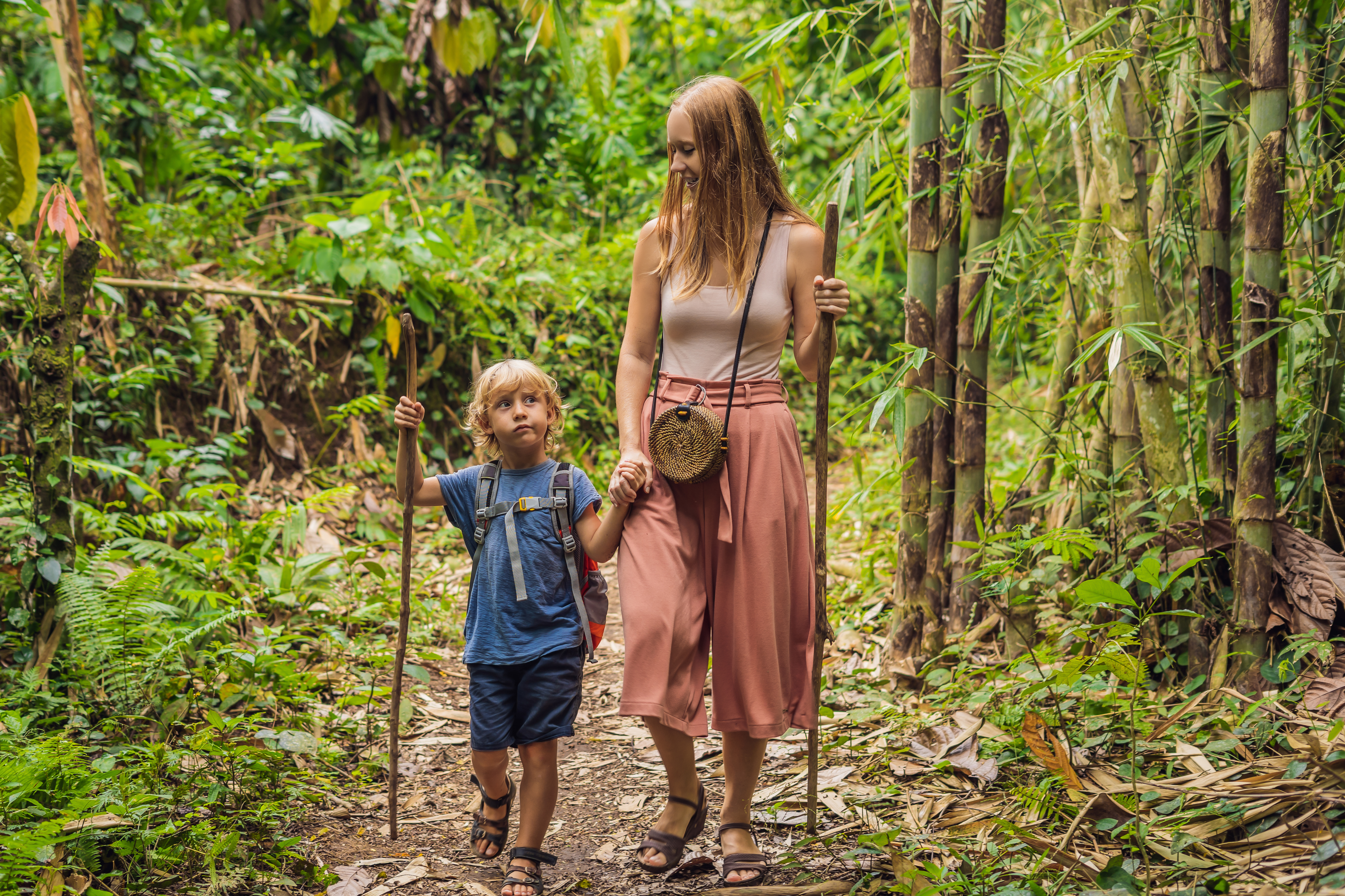 Family in hiking. Mom and son walking in the forest with trekking sticks famille en exploration dans la forêt tropicale de Guadeloupe